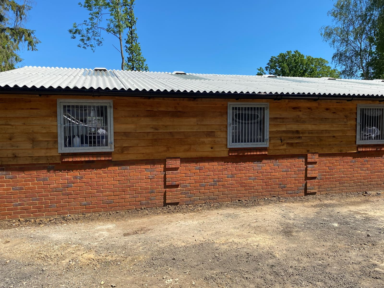 Newly built brick and timber-clad building with a corrugated roof under a blue sky